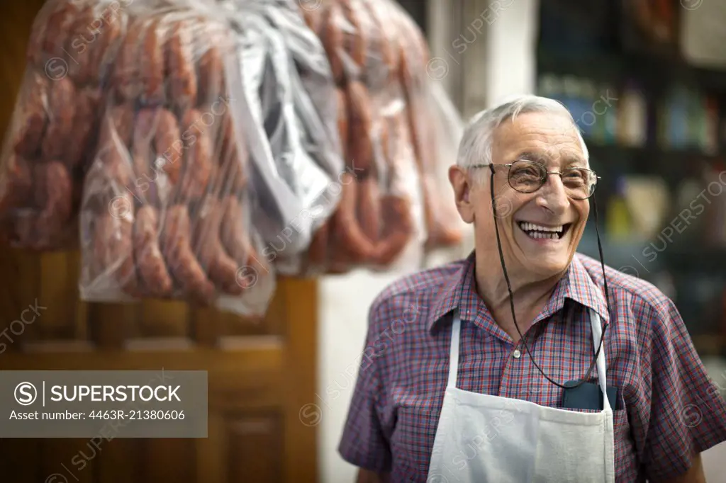 Portrait of cheerful elderly butcher at work.