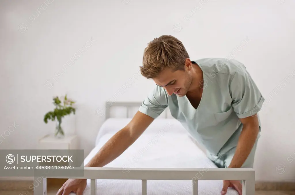 Male nurse making hospital bed. 