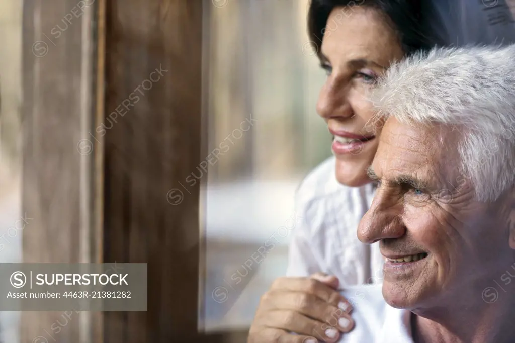 Loving mature couple looking through window.