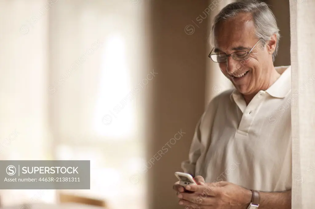 Smiling mature man, using cell phone.