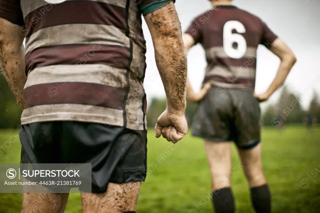 Rear view of two muddy rugby players on the field. 