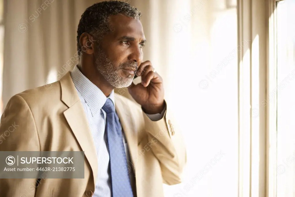 Angry-looking businessman talking on cell phone. 