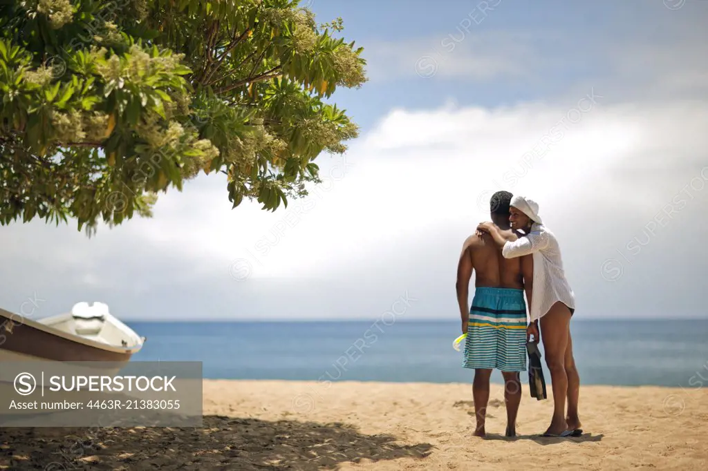 Mature woman hugging her husband at the beach.