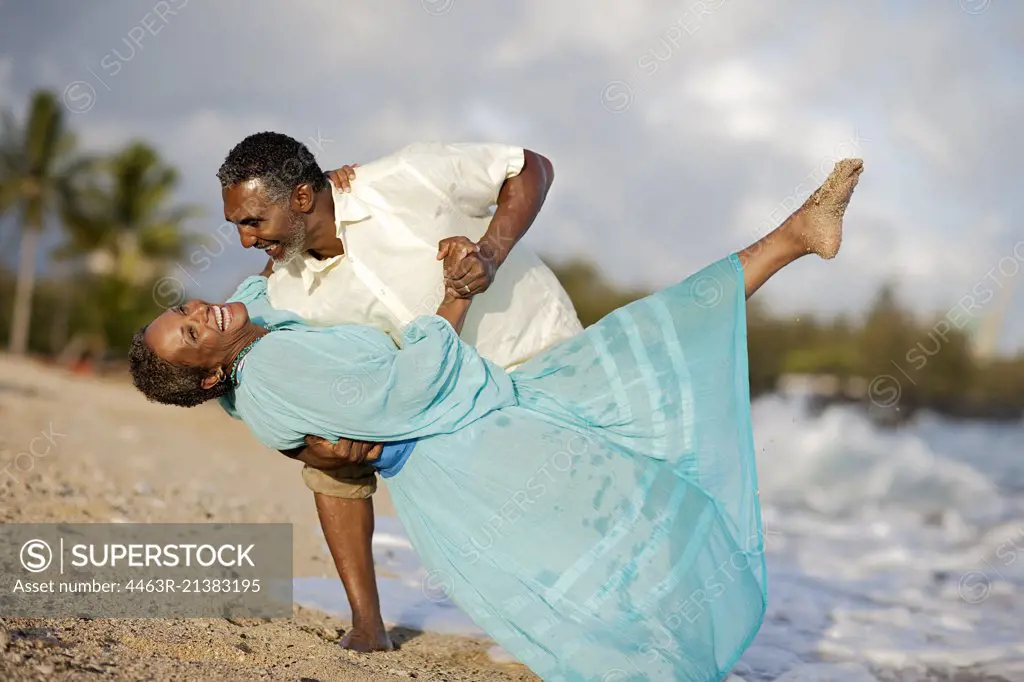 Happy mature couple dancing on the beach.