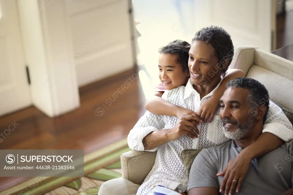 Smiling mature couple enjoying time with their granddaughter inside their home.