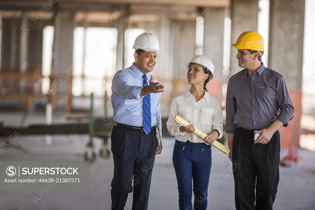 An architect and two executives talk on construction site.