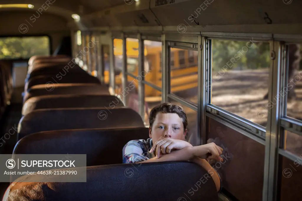 Portrait of a teenage boy sitting in an empty bus.