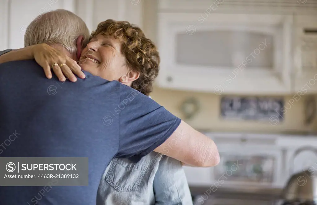 Mature couple embracing in their kitchen.