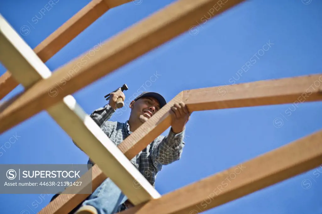 Builder picking up a hammer on a building site.