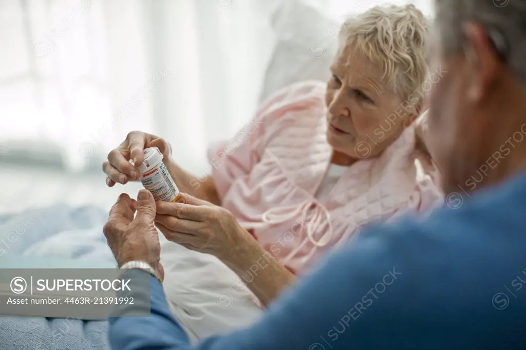 Senior man helping his puzzled wife read the instructions on her medicine bottle.