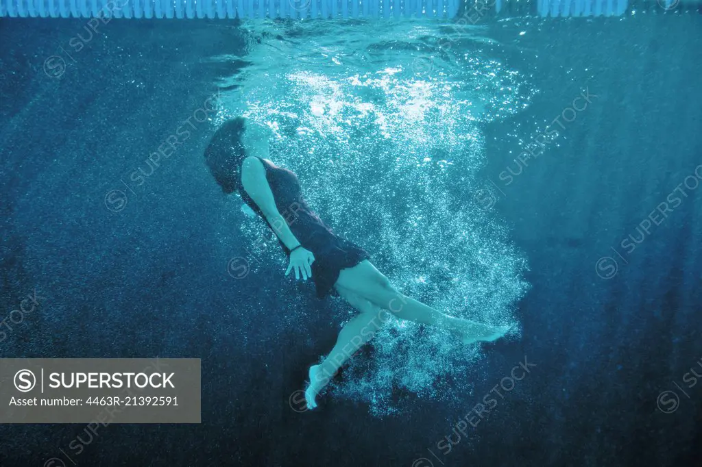 Woman wearing a dress swimming underwater.