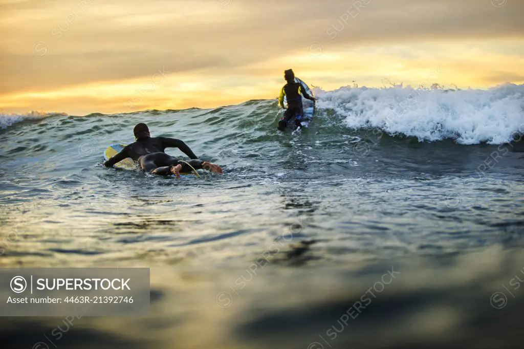 Father and daughter surfing at sunset.