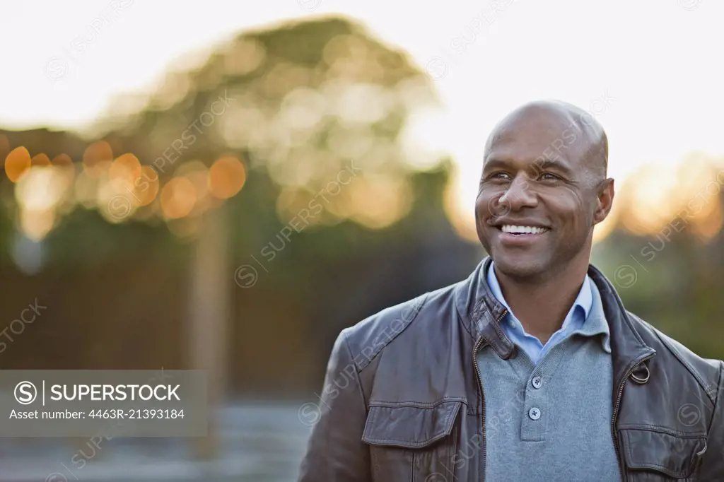 Smiling man stands in park