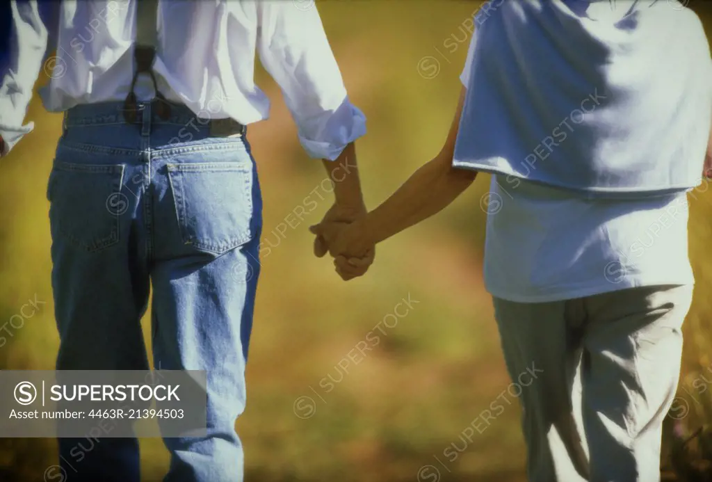 A couple is holding hands and walking.