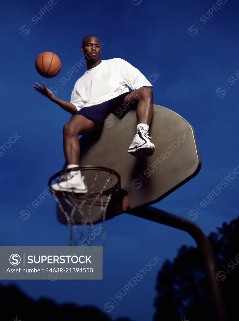 Basketball player atop blackboard tossing ball