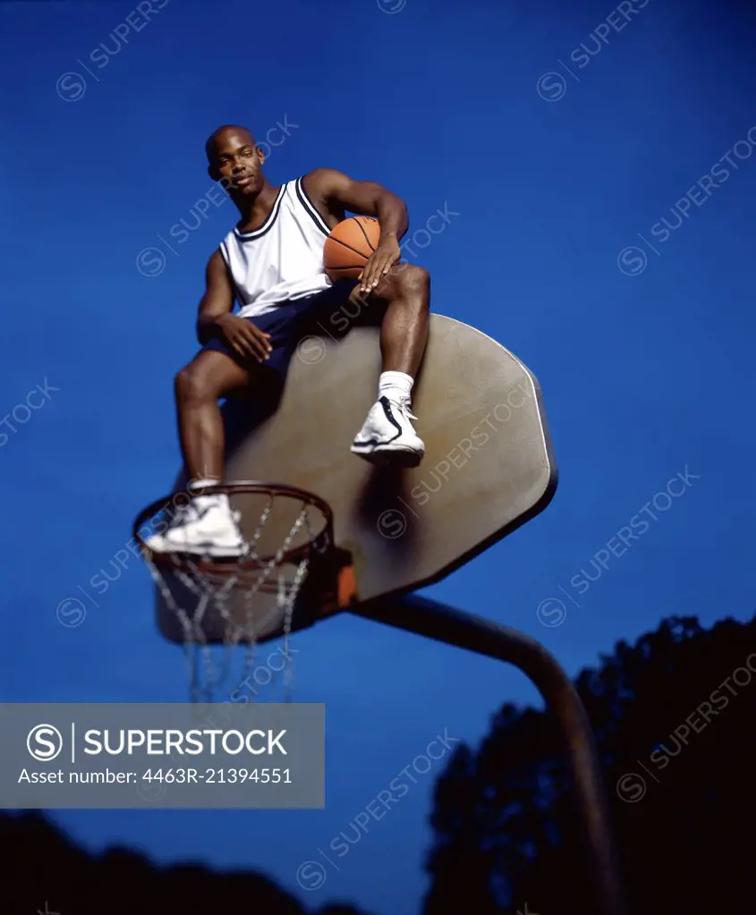Basketball player atop backboard