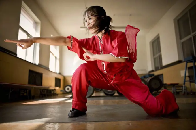 Teenage girl performing martial arts in a gym.
