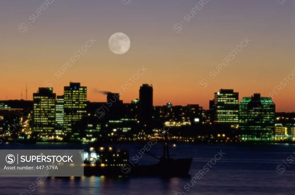 Silhouette of a boat on a river with high rise buildings at night in the background, Halifax, Nova Scotia, Canada