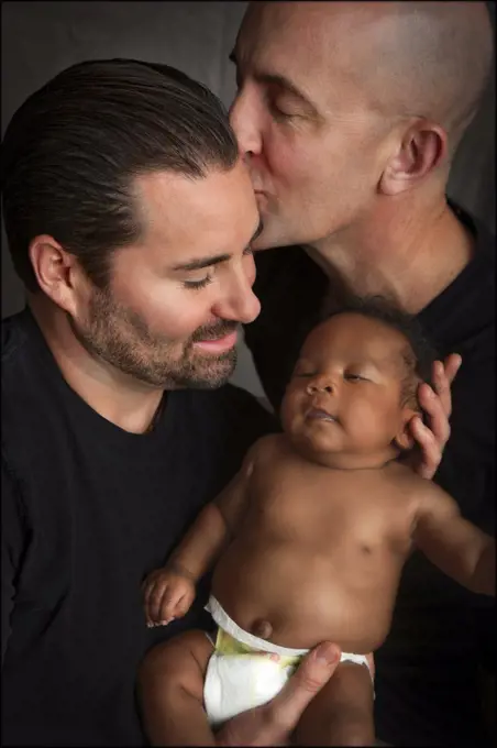 Couple Kissing While Holding Baby