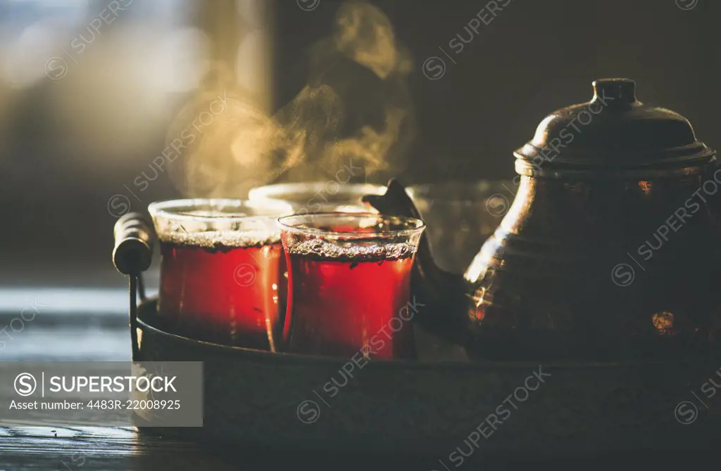 Freshly brewed black tea in turkish glasses and teapot in oriental tray, selective focus