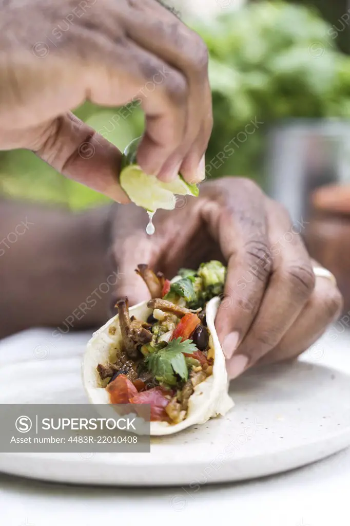 A man is squeezing lime on a slow cooked beef brisket chili taco while holding it with his other hand.