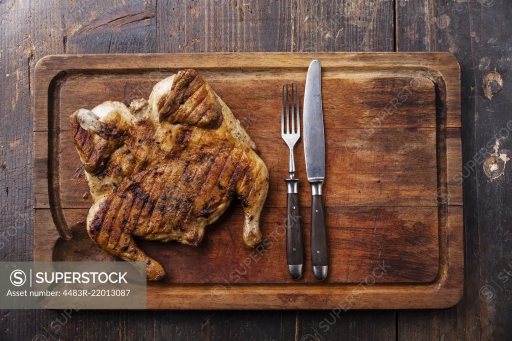 Grilled fried roast Chicken tobacco on cutting board on dark wooden background