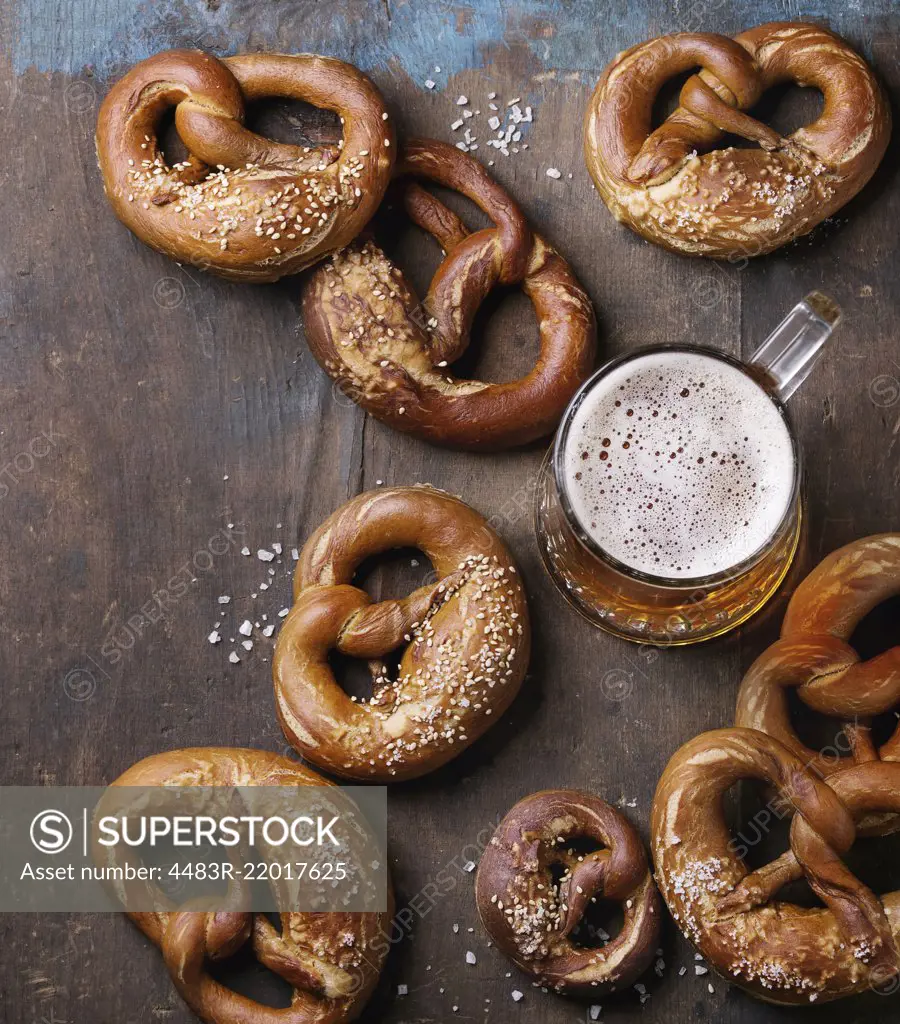 Glass of lager beer with traditional salted pretzels over old dark wooden background. Top view with space for text. Oktoberfest theme