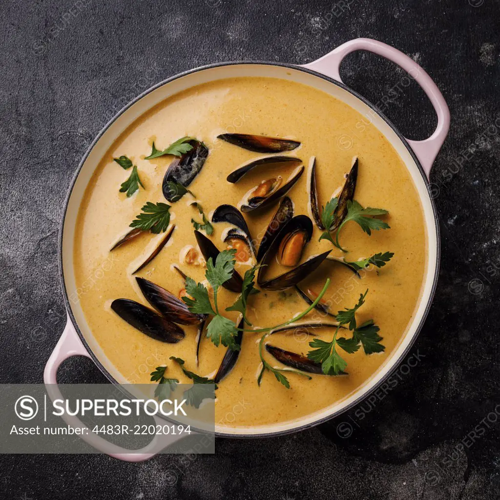 Seafood soup with shrimp and mussel in casserole on dark background