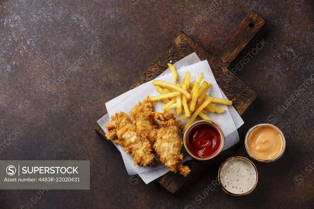 Fish and Chips british fast food with three popular sauce for choice on brown background copy space