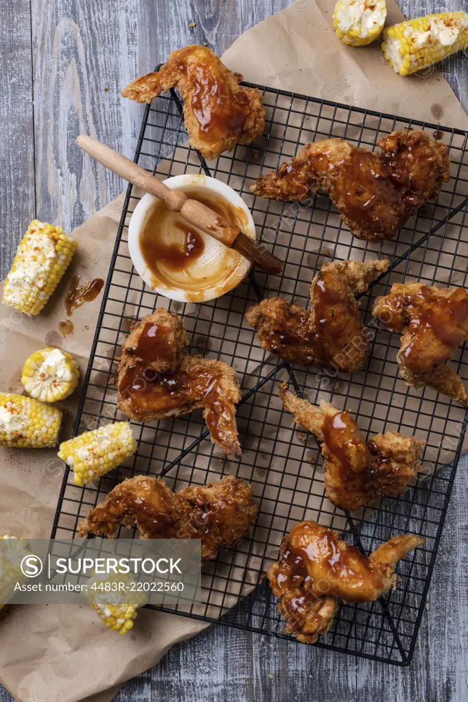 Fried Chicken wings with BBQ sauce and corn.