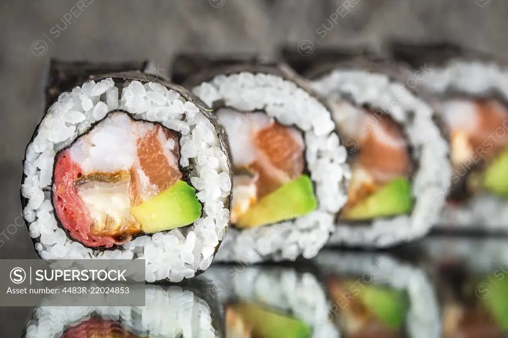 Sushi roll with salmon, shrimps and avocado over cocnrete background