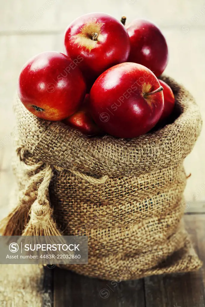 Burlap sack with apples on a wooden table