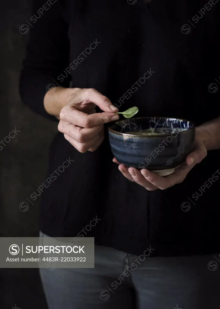 Person holding a basil leaf