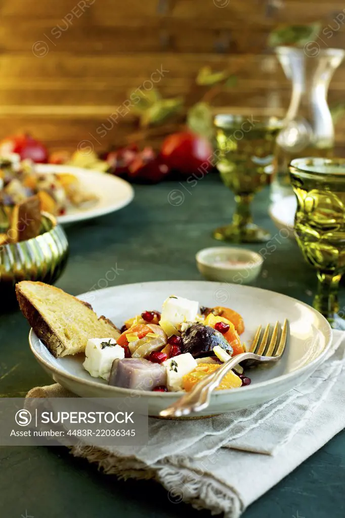 Olive Oil Wine Roasted Vegetable with Feta served with bread and wine. Photographed on a dark green background.