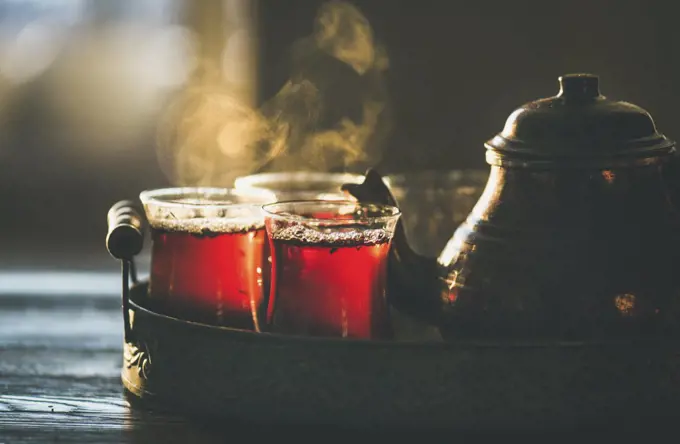 Freshly brewed black tea in turkish glasses and teapot in oriental tray, selective focus