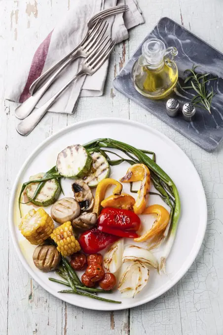 Grilled vegetables on the white plate on blue textured background