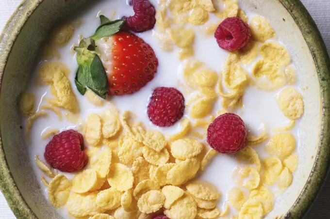 Cornflakes with milk and berries in ceramic bowl. Top view