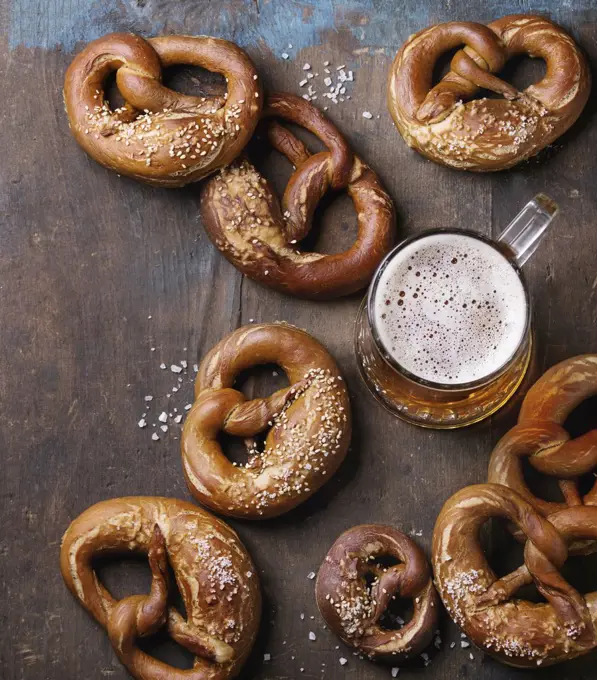 Glass of lager beer with traditional salted pretzels over old dark wooden background. Top view with space for text. Oktoberfest theme