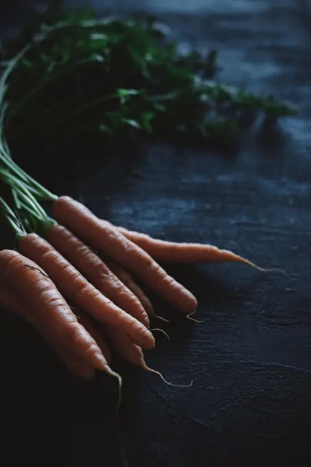 A carrot with stalk on a black background