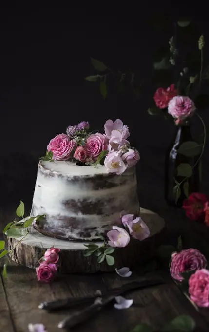 Naked cake decorated with roses on wooden table