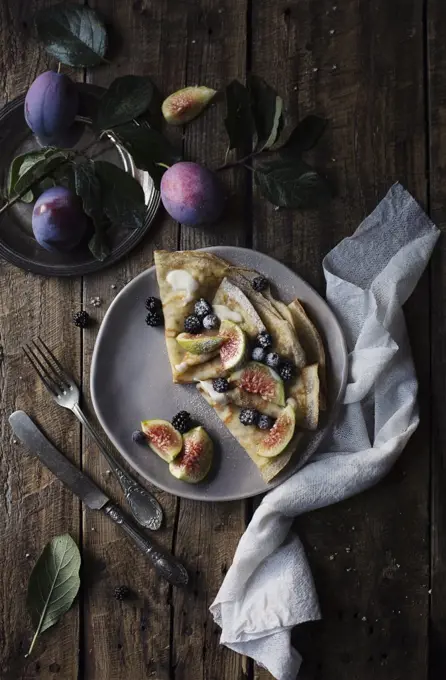 Crepes with figs and blackberries on wooden table. Top view