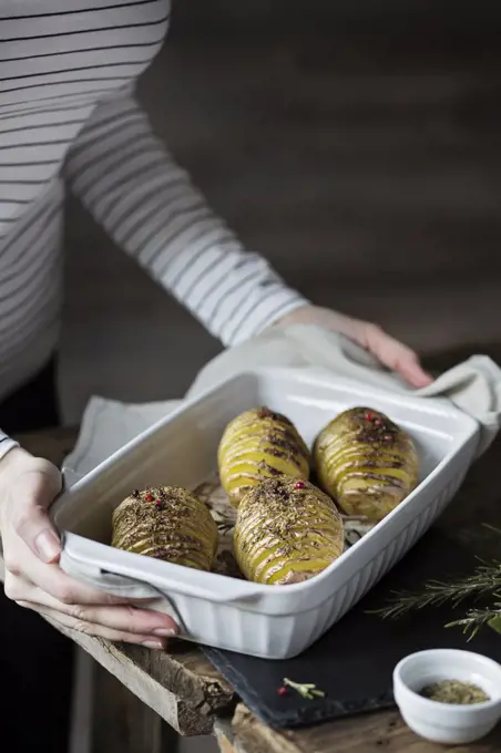 Woman with roasted hasselback potatoes