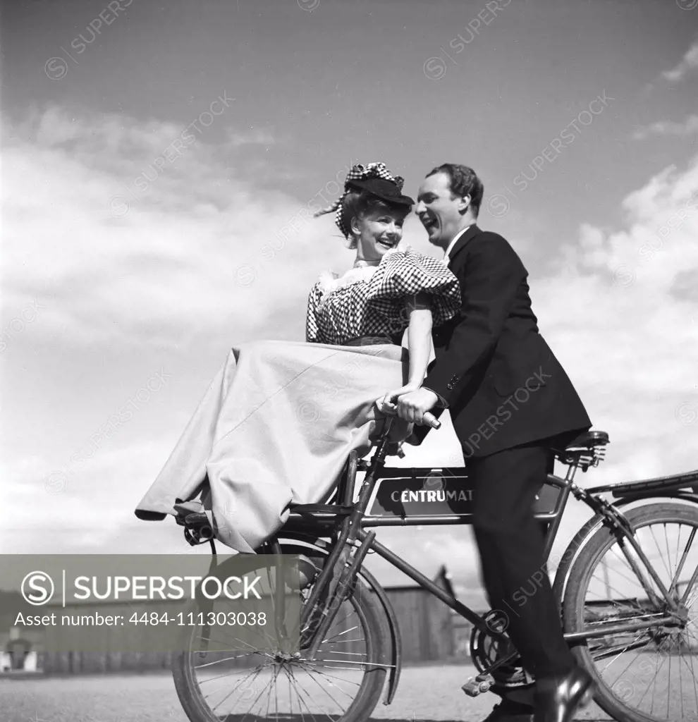1940s couple on a bicycle. A young couple is riding their bicycles on a sunny day. They are both actors; Sonja Wigert and Arnold Sjöstrand and they have some fun while recording their new film.  Sweden 1944. Photo Kristoffersson K23-6