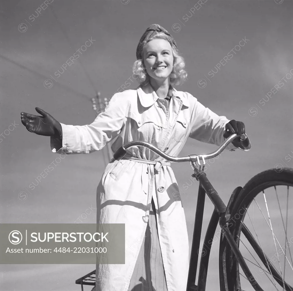 1940s woman on a bicycle. The Swedish actress Karin Nordgren is holding out her hand to give sign that she will turn right. Sweden 1940. Photo Kristoffersson 157-12