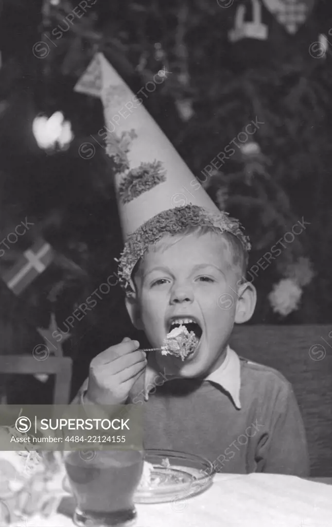 Christmas in the 1950s. A boy on a christmas party is eating cake and drinking lemonade. Sweden 1950s.
