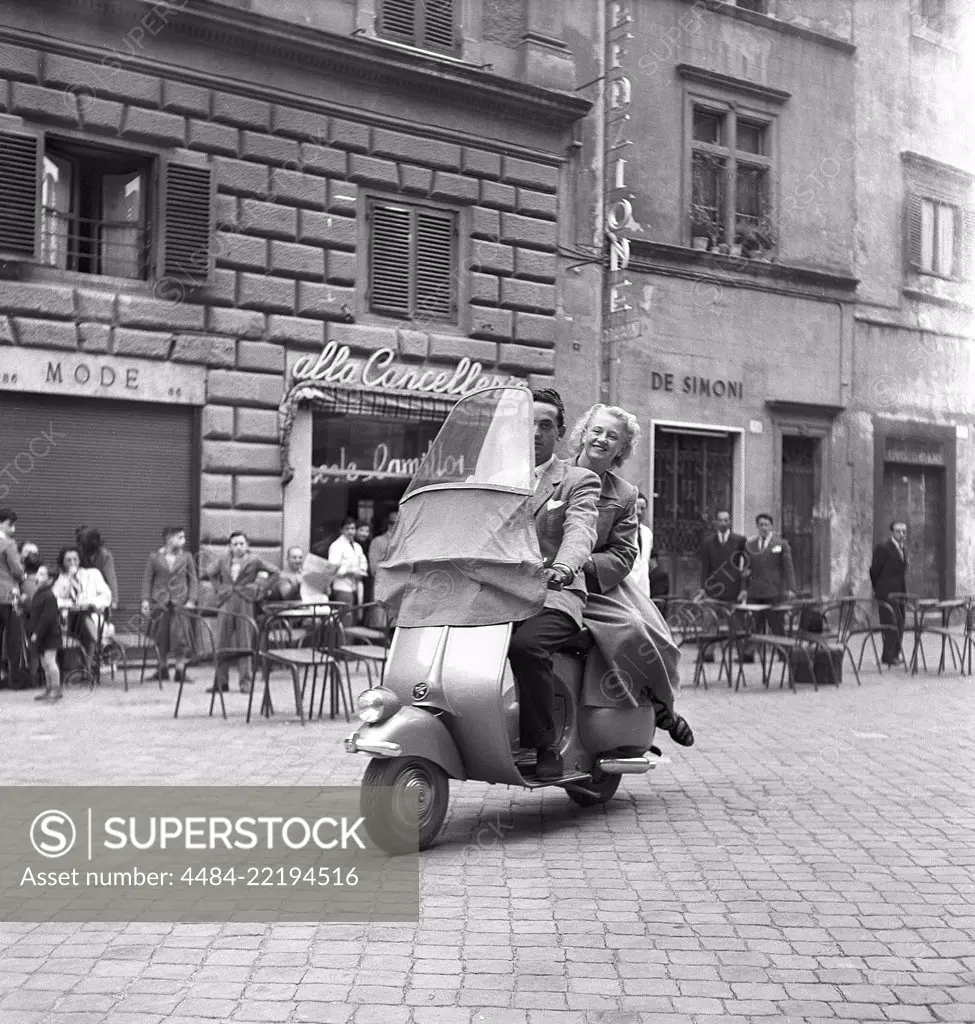 Couple in Italy in the 1950s. A young couple on a Vespa scooter driving on a street in Milan Italy 1950. Photo Kristoffersson Ref AY24-2