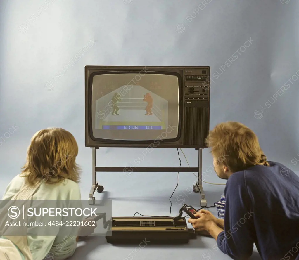 Home video games in the 1980s. A home video game console from Intellivison released by Mattel electronics in 1979. Pictured two people playing a boxing game on a television set.