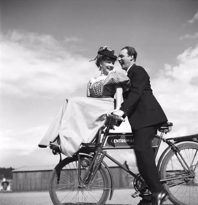 1940s couple on a bicycle. A young couple is riding their bicycles on a sunny day. They are both actors; Sonja Wigert and Arnold Sjöstrand and they have some fun while recording their new film.  Sweden 1944. Photo Kristoffersson K23-6