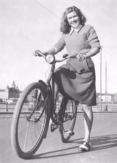 1940s woman on a bicycle. A smiling young woman on a womens bicycle on a sunny day. Swedish runner Anna Larsson. 1922-2003. Holder of four world records. Sweden 1940s
