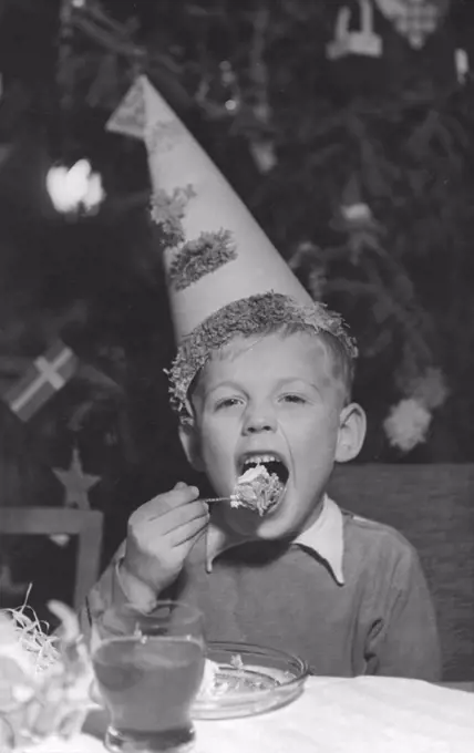Christmas in the 1950s. A boy on a christmas party is eating cake and drinking lemonade. Sweden 1950s.